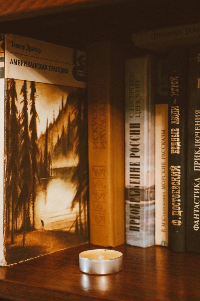 A cozy bookshelf with a variety of books and a candle adding ambient warm light, perfect for reading ambiance.